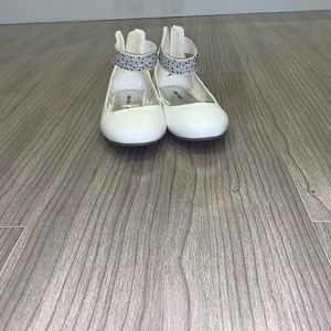 White Nine West flats with strap around the ankle and gems